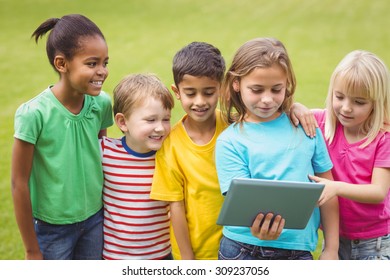 Smiling classmates looking at tablet on campus - Shutterstock ID 309237056