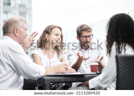 Smiling colleagues working together developing business strategy for their next project. asually dressed business people having discussion on sunny terrace. Modern job in comfortable conditions