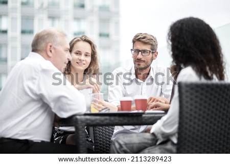 Smiling colleagues working together developing business strategy for their next project. asually dressed business people having discussion on sunny terrace. Modern job in comfortable conditions