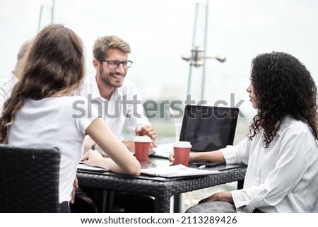 Smiling colleagues working together developing business strategy for their next project. asually dressed business people having discussion on sunny terrace. Modern job in comfortable conditions