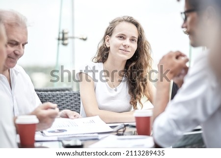 Smiling colleagues working together developing business strategy for their next project. asually dressed business people having discussion on sunny terrace. Modern job in comfortable conditions