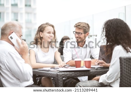 Smiling colleagues working together developing business strategy for their next project. asually dressed business people having discussion on sunny terrace. Modern job in comfortable conditions