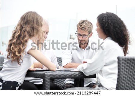 Smiling colleagues working together developing business strategy for their next project. asually dressed business people having discussion on sunny terrace. Modern job in comfortable conditions