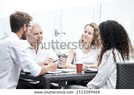 Smiling colleagues working together developing business strategy for their next project. asually dressed business people having discussion on sunny terrace. Modern job in comfortable conditions