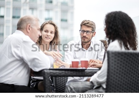 Smiling colleagues working together developing business strategy for their next project. asually dressed business people having discussion on sunny terrace. Modern job in comfortable conditions