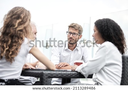Smiling colleagues working together developing business strategy for their next project. asually dressed business people having discussion on sunny terrace. Modern job in comfortable conditions