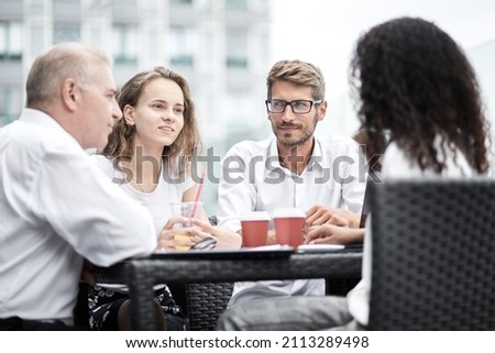 Smiling colleagues working together developing business strategy for their next project. asually dressed business people having discussion on sunny terrace. Modern job in comfortable conditions
