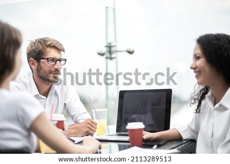 Smiling colleagues working together developing business strategy for their next project. asually dressed business people having discussion on sunny terrace. Modern job in comfortable conditions