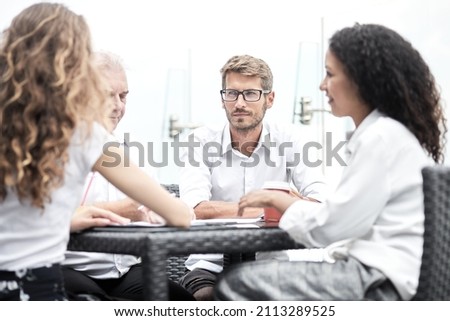 Smiling colleagues working together developing business strategy for their next project. asually dressed business people having discussion on sunny terrace. Modern job in comfortable conditions