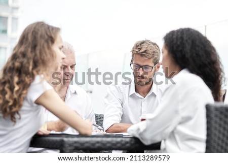 Smiling colleagues working together developing business strategy for their next project. asually dressed business people having discussion on sunny terrace. Modern job in comfortable conditions