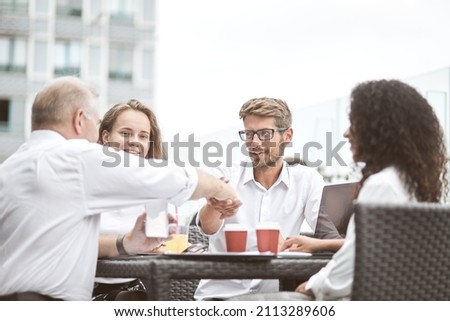 Smiling colleagues working together developing business strategy for their next project. asually dressed business people having discussion on sunny terrace. Modern job in comfortable conditions