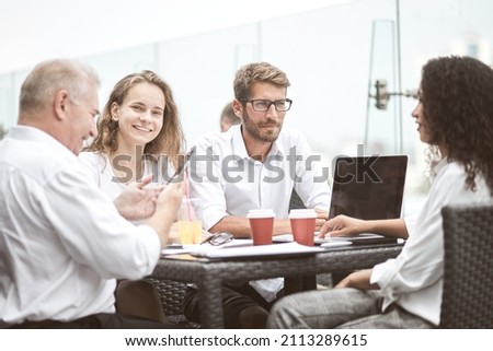 Smiling colleagues working together developing business strategy for their next project. asually dressed business people having discussion on sunny terrace. Modern job in comfortable conditions