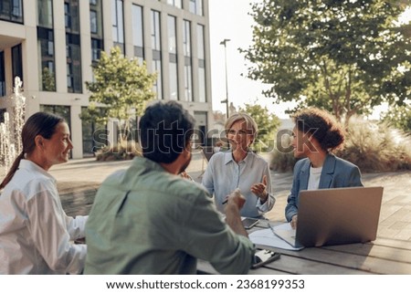 Smiling colleagues working together developing business strategy for project on office terrace