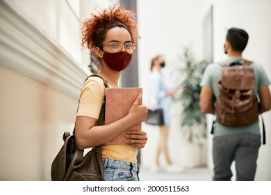 Smiling College Student Wearing Face Mask While Standing In Hallway And Looking At Camera.