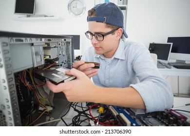 Smiling computer engineer working on broken console with screwdriver in his office