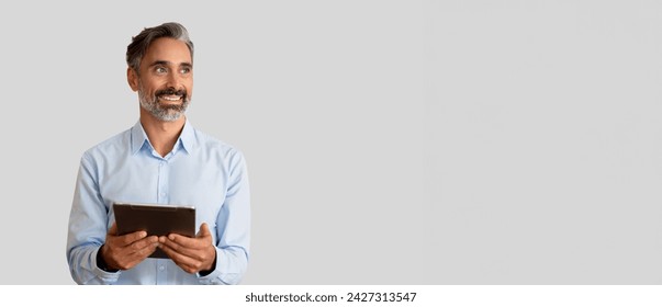 Smiling confident 40s latin hispanic mature business man holding digital tablet isolated on grey background. Older senior businessman, male leader professional using touchscreen pc. Banner, copy space - Powered by Shutterstock