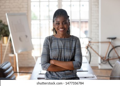 Smiling Confident African American Female Corporate Leader Executive Standing Arms Crossed In Modern Office Space Looking At Camera, Happy Entrepreneur Professional Business Woman Manager Portrait