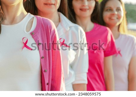 Smiling confident beautiful  women wearing  t shirts with breast cancer pink ribbon standing on the street. Health care, support, prevention. Breast cancer awareness month concept