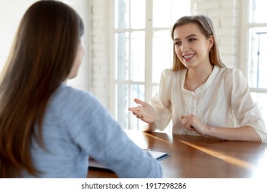 Smiling confident beautiful young woman involved in conversation with hr manager at meeting. Happy millennial female job seeker making self-presentation to employer, good first impression concept.