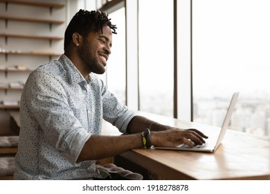 Smiling Confident Black African Male Correspond With Client Friend Online Typing Texting Email Message On Laptop Keyboard. Happy Young Afro Man Skilled Gamer Enjoy Playing Pc Video Game In Good Mood