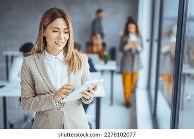Smiling confident business leader looking at camera and standing in an office at team meeting. Portrait of confident businesswoman with colleagues in boardroom. Using digital tablet during a meeting. - Shutterstock ID 2278102077