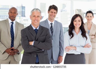 Smiling and confident business team standing in front of a bright window