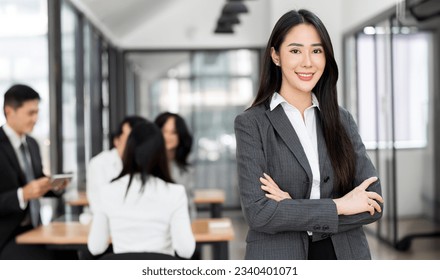 Smiling confident businesswoman looking at camera and standing in an office at team meeting. Portrait of confident businesswoman with colleagues in boardroom.  - Shutterstock ID 2340401071