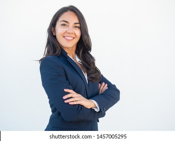 Smiling confident businesswoman posing with arms folded. Happy beautiful black haired young Latin woman in formal suit standing for camera over white studio background. Corporate portrait concept - Shutterstock ID 1457005295