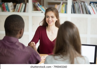Smiling confident female applicant shaking hand of african hr manager making good first impression, employer congratulates attractive happy woman candidate getting hired, employment handshake concept