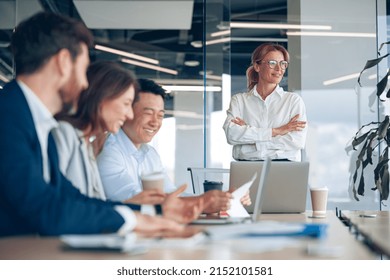 Smiling Confident Female Boss Looking At Side On Business Meeting With Colleagues In Office