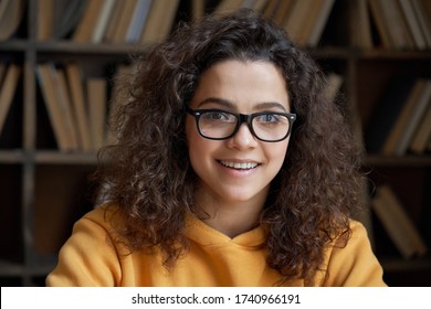 Smiling Confident Latin Teen Girl School Pupil, College Student Or University Teacher Looking At Camera. Happy Hispanic Woman Wear Glasses Posing In Library Classroom. Close Up Headshot Portrait.