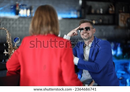 Smiling confident man in sunglasses meets woman near bar counter. Narcissistic personality disorder in men concept