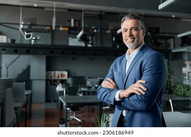 Smiling confident middle aged business man, mature older professional successful company ceo corporate leader wearing blue suit standing in modern office with arms crossed looking at camera, portrait. - Shutterstock ID 2306186949