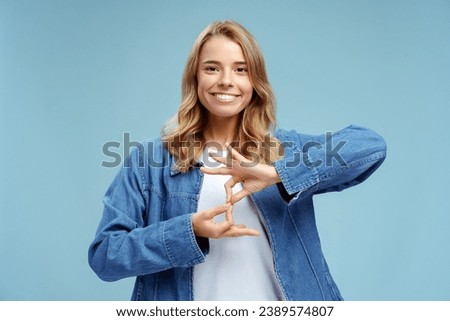 Smiling confident sign language interpreter or teacher communicating by hands gestures isolated on blue background. Nonverbal communication concept