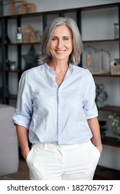 Smiling confident stylish mature middle aged woman stand at home office. Old senior elegant businesswoman, 60s gray-haired lady executive business leader manager looking at camera, vertical portrait. - Shutterstock ID 1827057917