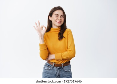 Smiling confident woman assure and guarantee all good, showing okay sign, have situation under control, like and praise promo offer, white background. - Shutterstock ID 1927519646