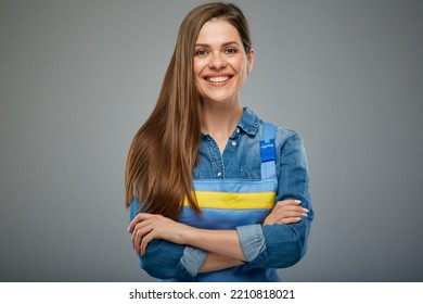 Smiling confident woman builder in blue overalls standing with arms crossed.