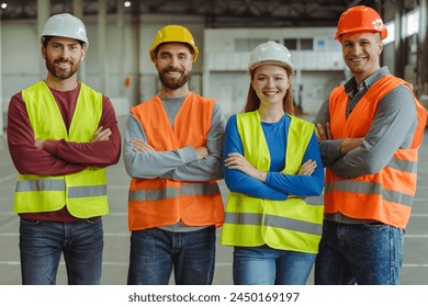 Smiling confident workers, engineers wearing hard hats and work wear with arms crossed looking at camera, posing in warehouse. Concept of teamwork, logistics, industry - Powered by Shutterstock