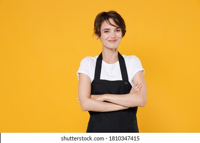 Smiling Confident Young Woman 20s Barista Bartender Barman Employee In White T-shirt Apron Work In Coffee Shop Holding Hands Crossed Looking Camera Isolated On Yellow Color Background Studio Portrait