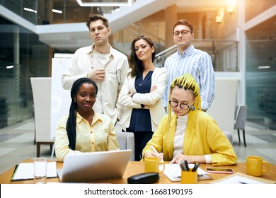 Smiling Confident Young Woman In Blue Elegant Jacket Standing Among Cheerful People, Close Up Photo, Team , Partnership , Glass Wall In The Background Of The Photo.