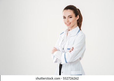 Smiling confident young woman doctor standing with arms crossed over white background