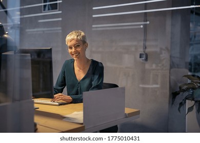 Smiling Cool Business Woman Working On Desktop Computer Late At Night. Beautiful Stylish Business Woman Working. Portrait Of Trendy Girl Using Computer Late In The Evening In Office With Copy Space.