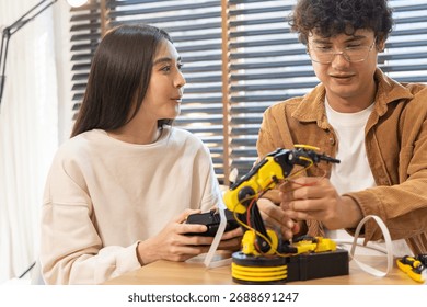 Smiling couple assembling and testing a yellow robotic arm with tools on a table, engaging in a fun DIY tech project indoors.