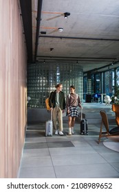 Smiling couple with baggage walking in hotel lobby