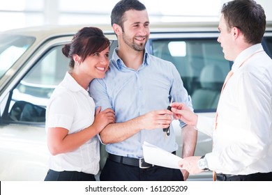 Smiling couple buying a new car from a salesman