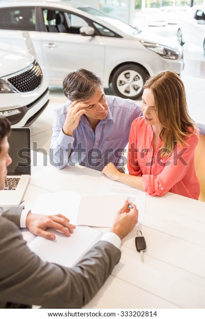 Smiling\
couple buying a new car at new car\
showroom