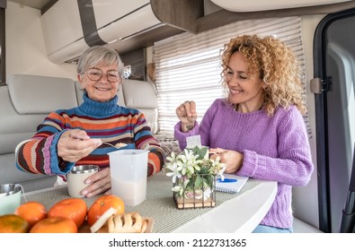 Smiling Couple Of Caucasian Women Multigenerational Family Friends Sitting Inside A Camper Van Motor Home Relaxing With A Herbal The. Lifestyle And Travel Modern People, Vacation Journey Concept