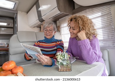 Smiling Couple Of Caucasian Women Multigenerational Family Sitting Inside A Camper Van Motor Home Looking At Map Planning Next Journey. Lifestyle And Travel Modern People, Vacation Journey Concept