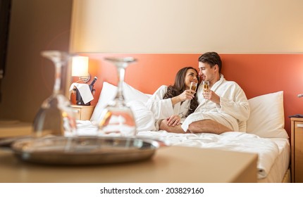 Smiling Couple With Champagne Glasses In Bed