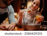 Smiling couple in a cozy kitchen adding honey to a mixing bowl. They are enjoying baking, creating a warm and inviting atmosphere with natural ingredients and teamwork